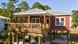 A two-story house with a wooden deck and a covered porch. - Bienville Bungalow - 304 Bienville Blvd 2 Bedroom Home (Dauphin Island)