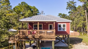 A two-story house with a wooden deck and a covered porch. - Bienville Bungalow - 304 Bienville Blvd 2 Bedroom Home (Dauphin Island)