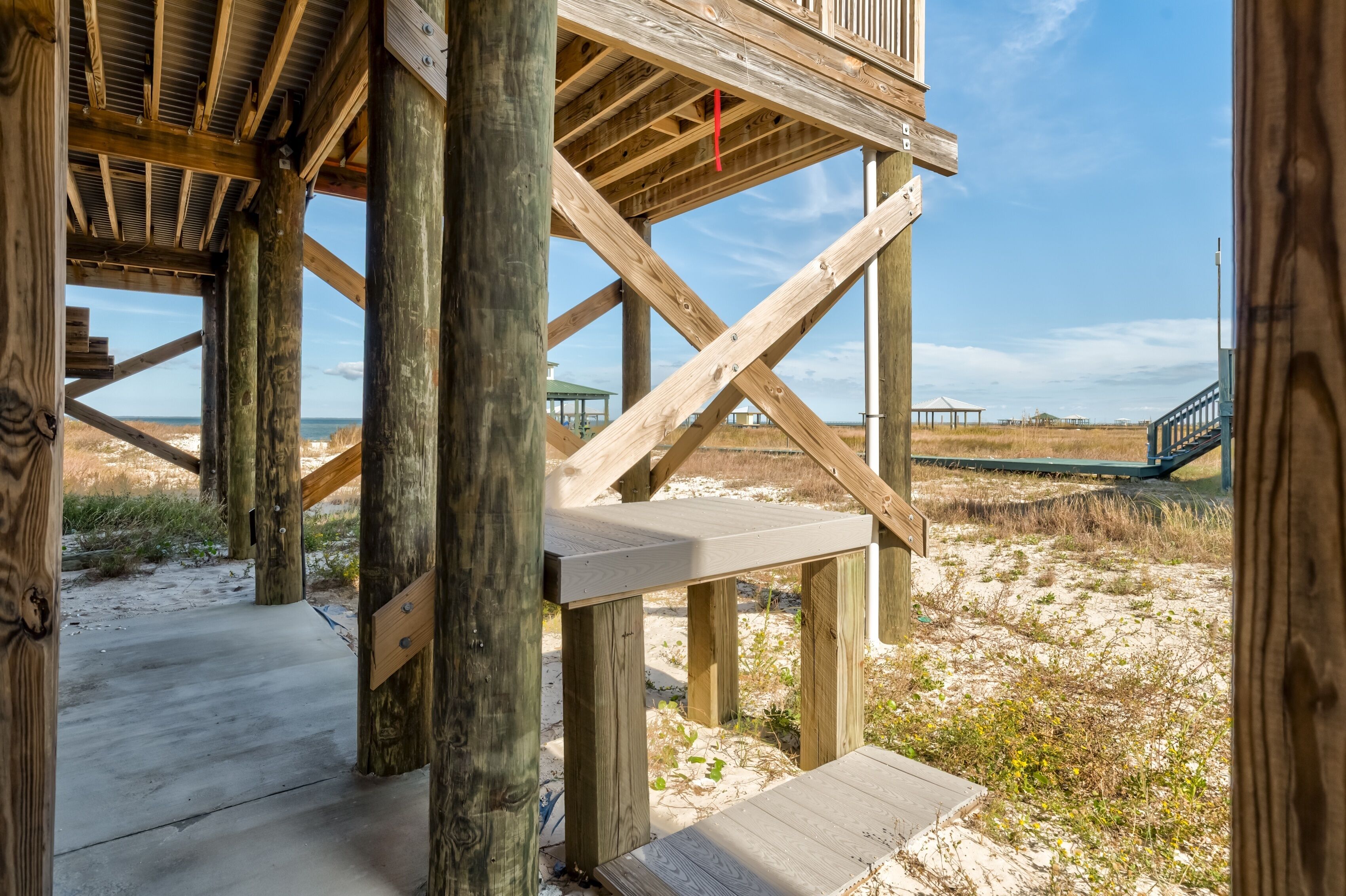 A wooden pier structure with a concrete walkway leading to a sandy beach area.