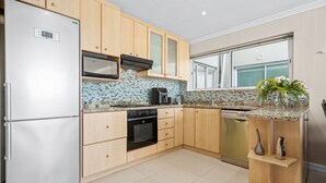 Una cocina moderna con armarios de madera, un refrigerador de acero inoxidable, un microondas, un horno y un lavavajillas.