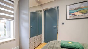 Ein Schlafzimmer mit Bett, Fenster, Kleiderschrank und einem gerahmten Bild an der Wand.