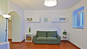 Un salon moderne avec un canapé vert, une lampe blanche et un luminaire suspendu au plafond.