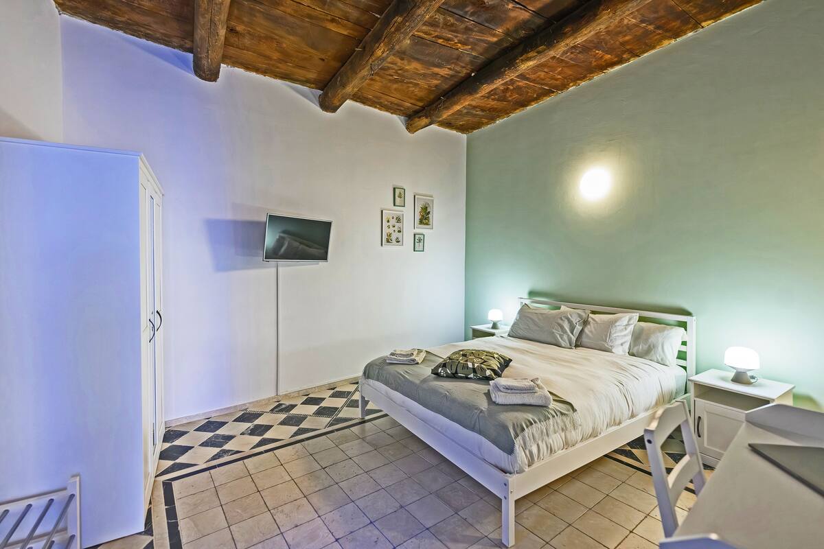 Ein Schlafzimmer mit Bett, Fernseher, Nachttisch und Schreibtisch.
