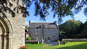 A stone building with a traditional architectural style, a paved pathway leading to the entrance, and a well-maintained lawn. - Spacious Family Home with Private Terrace, Garden & Wi-Fi in Saint Lormel (Saint Lormel)
