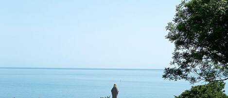 A stone monument with a circular base, surrounded by a grassy area with a clear view of the sea.
