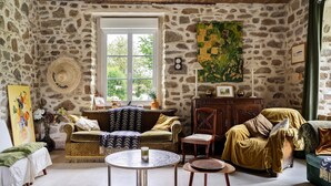 A stone-walled room with a sofa, a chair, a table, and a window. - Spacious Family Home with Private Terrace, Garden & Wi-Fi in Saint Lormel (Saint Lormel)