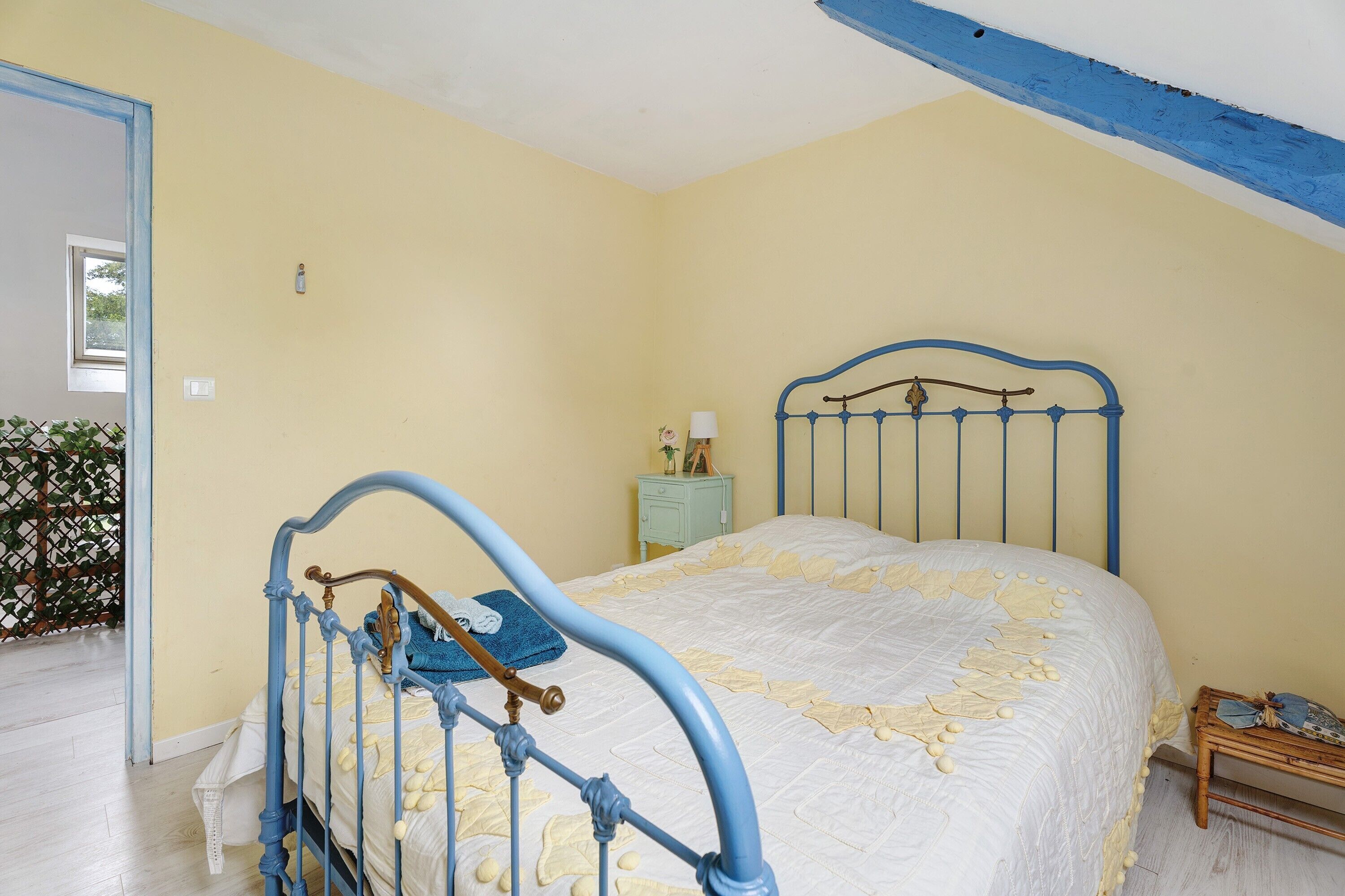 A bedroom with a bed, a nightstand, and a window.