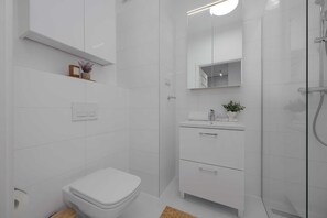 Een moderne badkamer met toilet, wastafel met spiegel en douche.