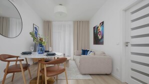 A modern living room with a round dining table, brown leather chairs, a beige sofa, and a colorful abstract painting on the wall. - Stylish Apartment with Balcony | Air Conditioning | Close to the Metro (Warszawa)