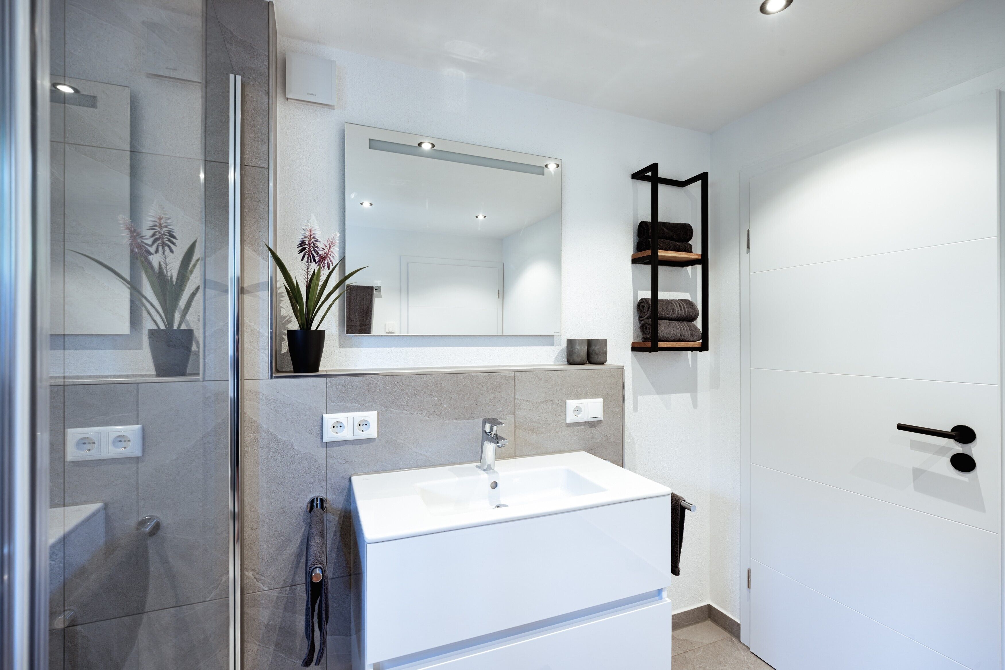 Ein modernes Badezimmer mit Waschbecken, Spiegel und Handtuchhalter in Weiß.