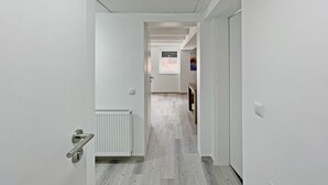 A narrow hallway with a radiator, a door with a handle, and a wall-mounted light switch. - Apartment '6' with Private Terrace, Shared Garden and Wi-Fi (Ichenhausen)