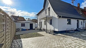 A residential building with a sloped roof, a balcony, and a paved courtyard. - Apartment '6' with Private Terrace, Shared Garden and Wi-Fi (Ichenhausen)