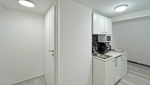 A modern kitchen with white cabinets, a microwave, and a coffee machine. - Apartment '6' with Private Terrace, Shared Garden and Wi-Fi (Ichenhausen)