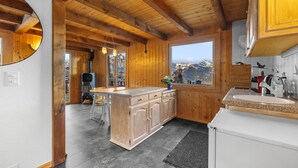 A wooden cabin interior with a kitchen area, a dining space, and a view of mountains. - Le Petiot - mini chalet - maxi douceur - 4p (Haute-Nendaz)