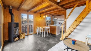 A wooden cabin with a dining area, kitchen, and a fireplace. - Le Petiot - mini chalet - maxi douceur - 4p (Haute-Nendaz)