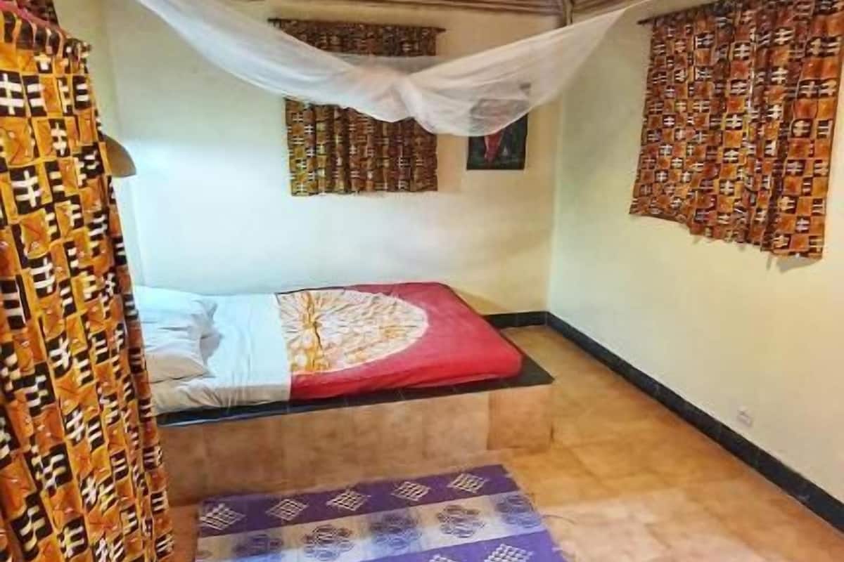 Quarto com cama, tapete, luminária pendente e cortinas estampadas.