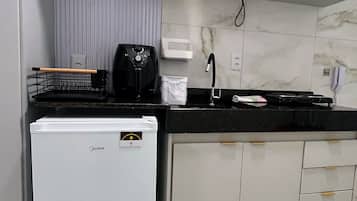 A compact kitchen with a refrigerator, a coffee maker, a microwave, and a sink.