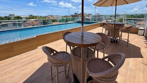 A rooftop terrace with a pool, wicker furniture, and a view of the city. - Waikiki Garden (Ipojuca)