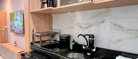 A modern kitchen with a black countertop, stainless steel sink, and built-in appliances.