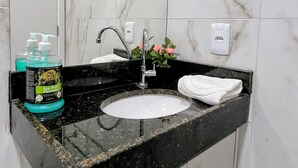 A bathroom with a white sink, black countertop, and marble walls. - Waikiki Garden (Ipojuca)