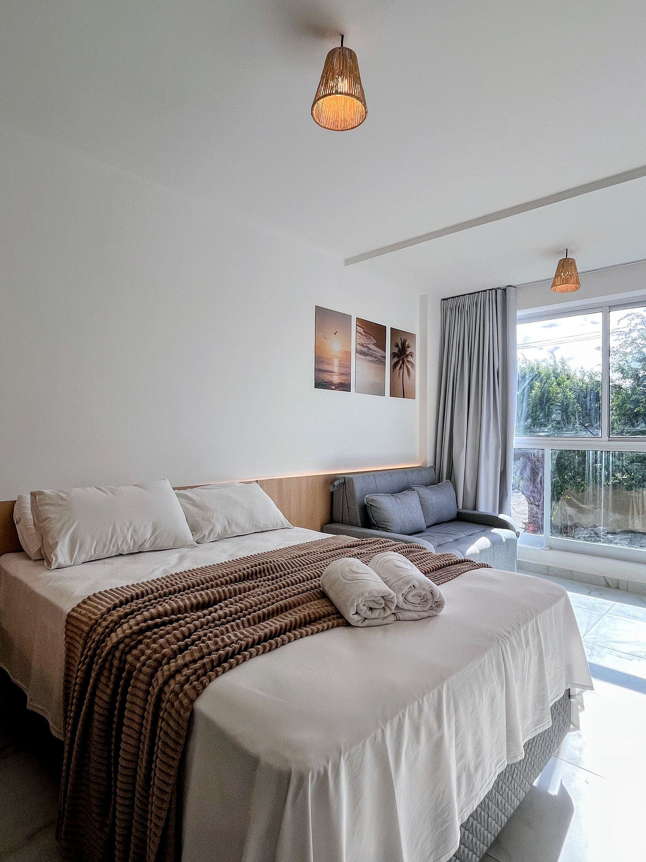 Una habitación de hotel con cama, sofá, ventana con cortinas y decoración en la pared.