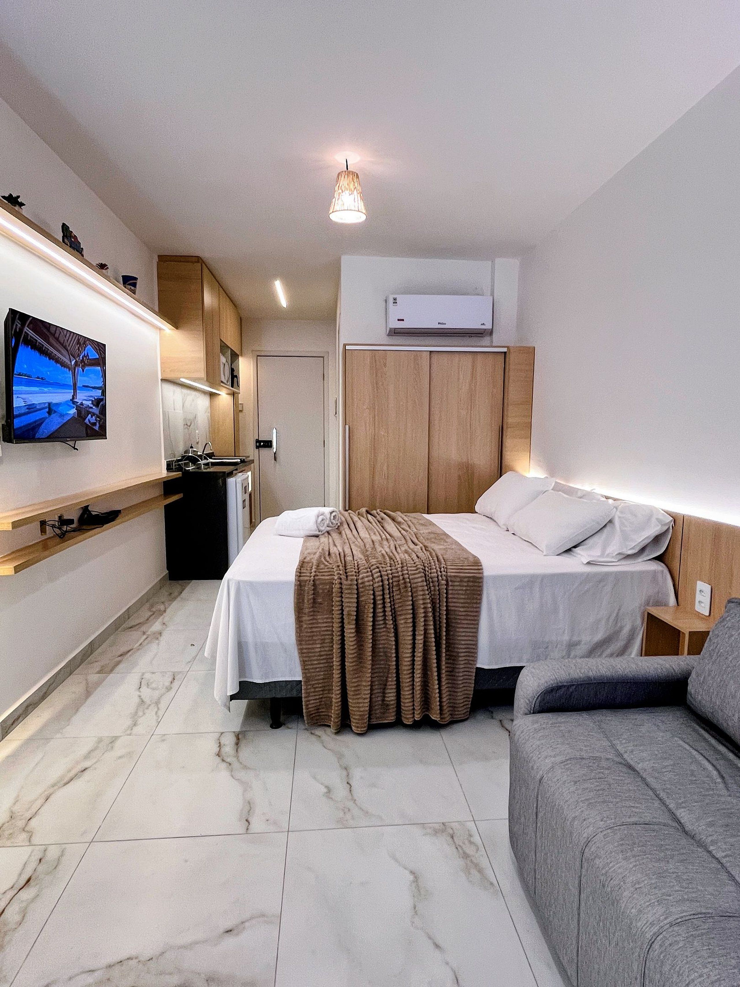 Une chambre d’hôtel équipée d’un lit, d’un canapé, d’une télévision, d’un coin cuisine et d’un appareil de climatisation.