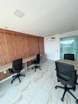 A modern office space with a long wooden panel wall, a glass door, and a tiled floor. - Waikiki Garden (Ipojuca)