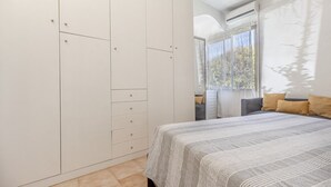 Ein Schlafzimmer mit einem großen Bett, einem Kleiderschrank und einem Fenster mit Vorhängen.