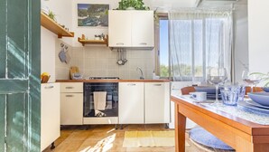 Eine moderne Küche mit weißen Schränken, einem eingebauten Backofen und einem Fenster mit transparenten Vorhängen.