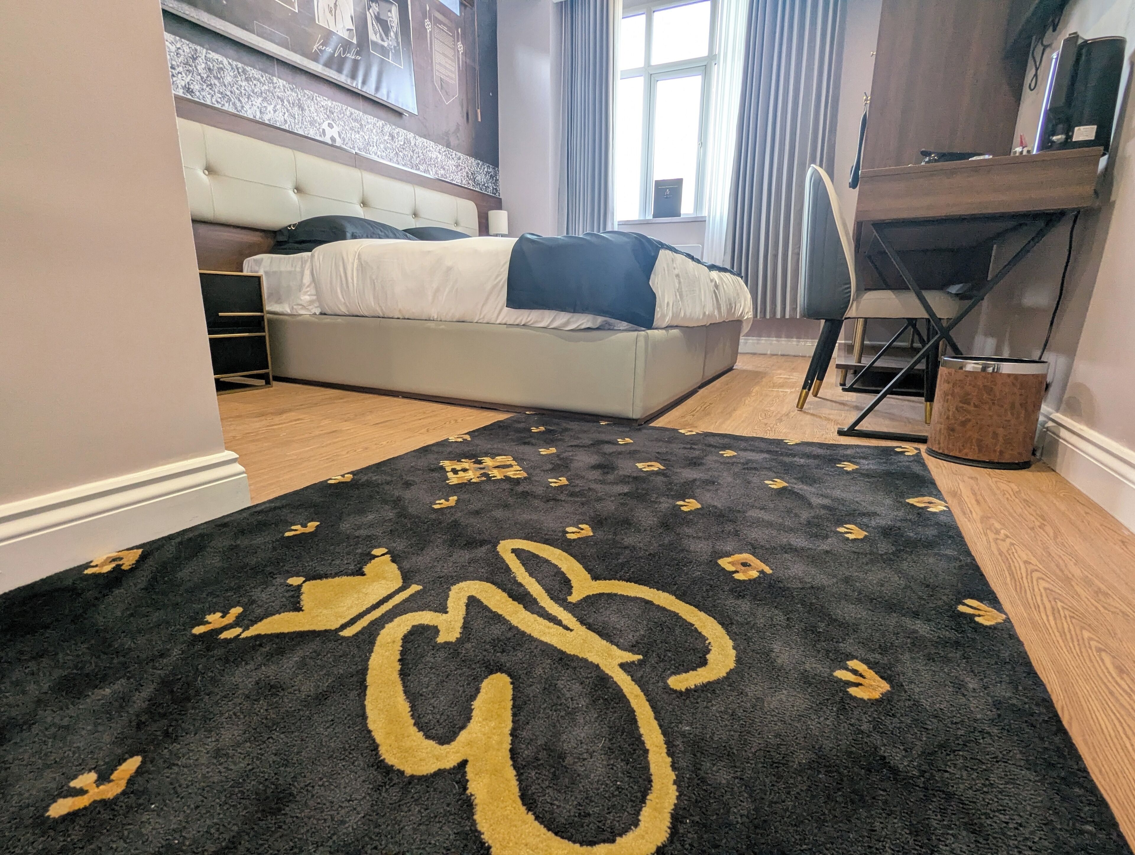 A bedroom with a bed, a desk, and a window.