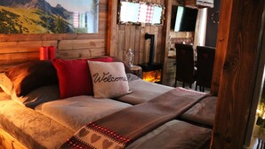 Ein gemütliches Zimmer mit Bett, Kopfkissen, Fernseher und Kamin.