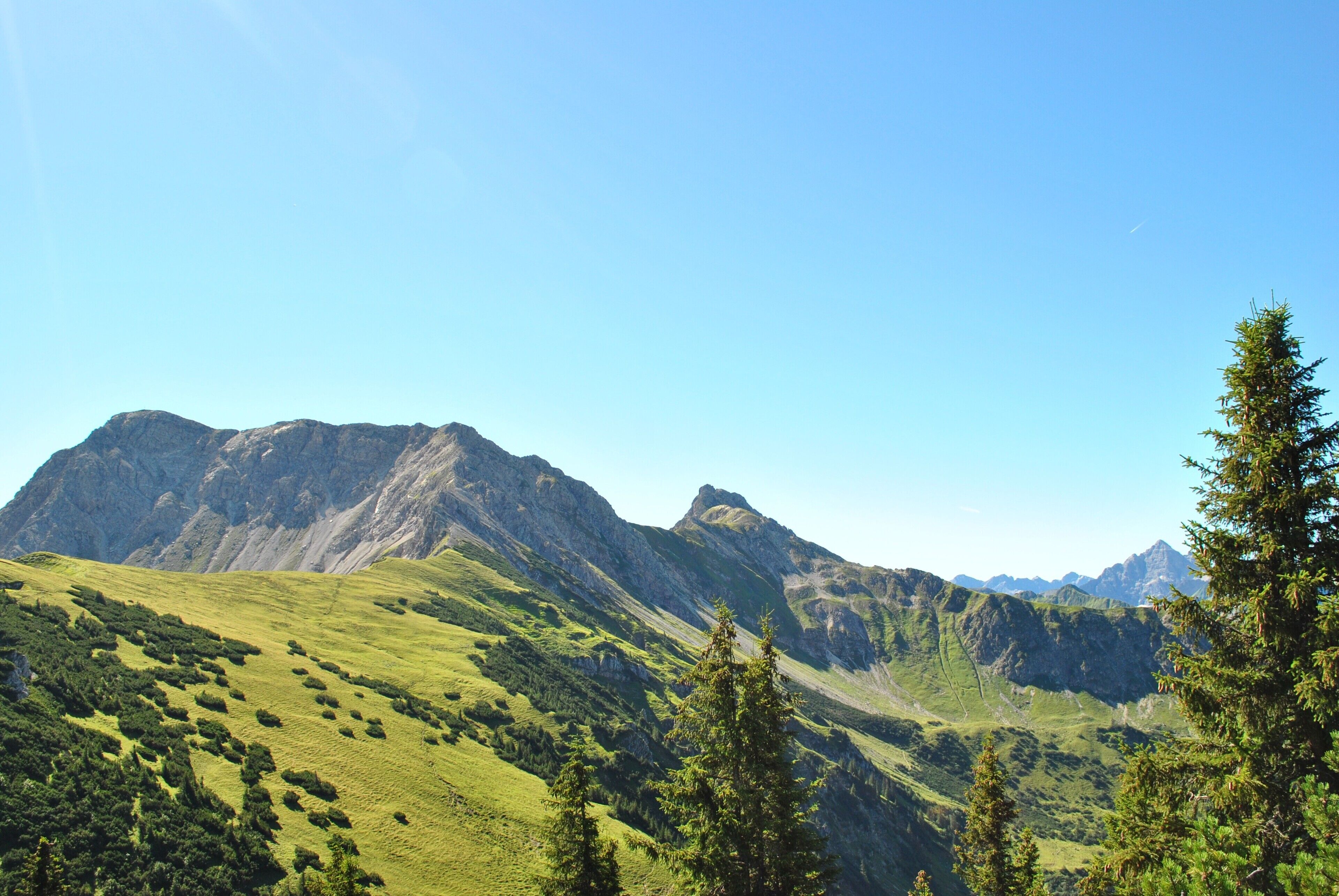 A mountainous landscape with green hills and rocky peaks.
