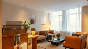 A modern hotel room with a sofa, armchairs, a coffee table, a desk, and a lamp. - Hotel Middelland Rotterdam (Rotterdam)
