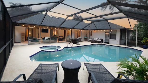 En swimmingpool med en overdækket terrasse, liggestole og siddepladser.