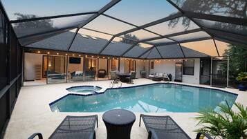 Ein Schwimmbad mit überdachter Terrasse, Liegestühlen und einer Sitzecke.