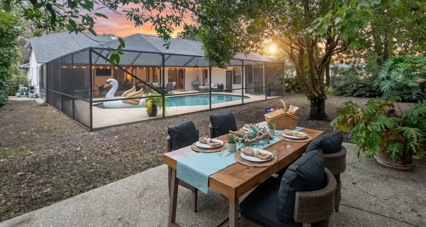 Ein Garten mit Pool, einem Esstisch für vier Personen und einer überdachten Sitzgelegenheit.