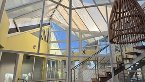 Ein modernes Interieur mit Glasdecke, einer Holztreppe und einer hängenden Leuchte.