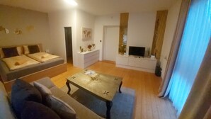 A living room with a sofa, a coffee table, a TV, and a white cabinet. - Apartment 'Golden Base' with Mountain View, Wi-Fi and Air Conditioning (Villach)