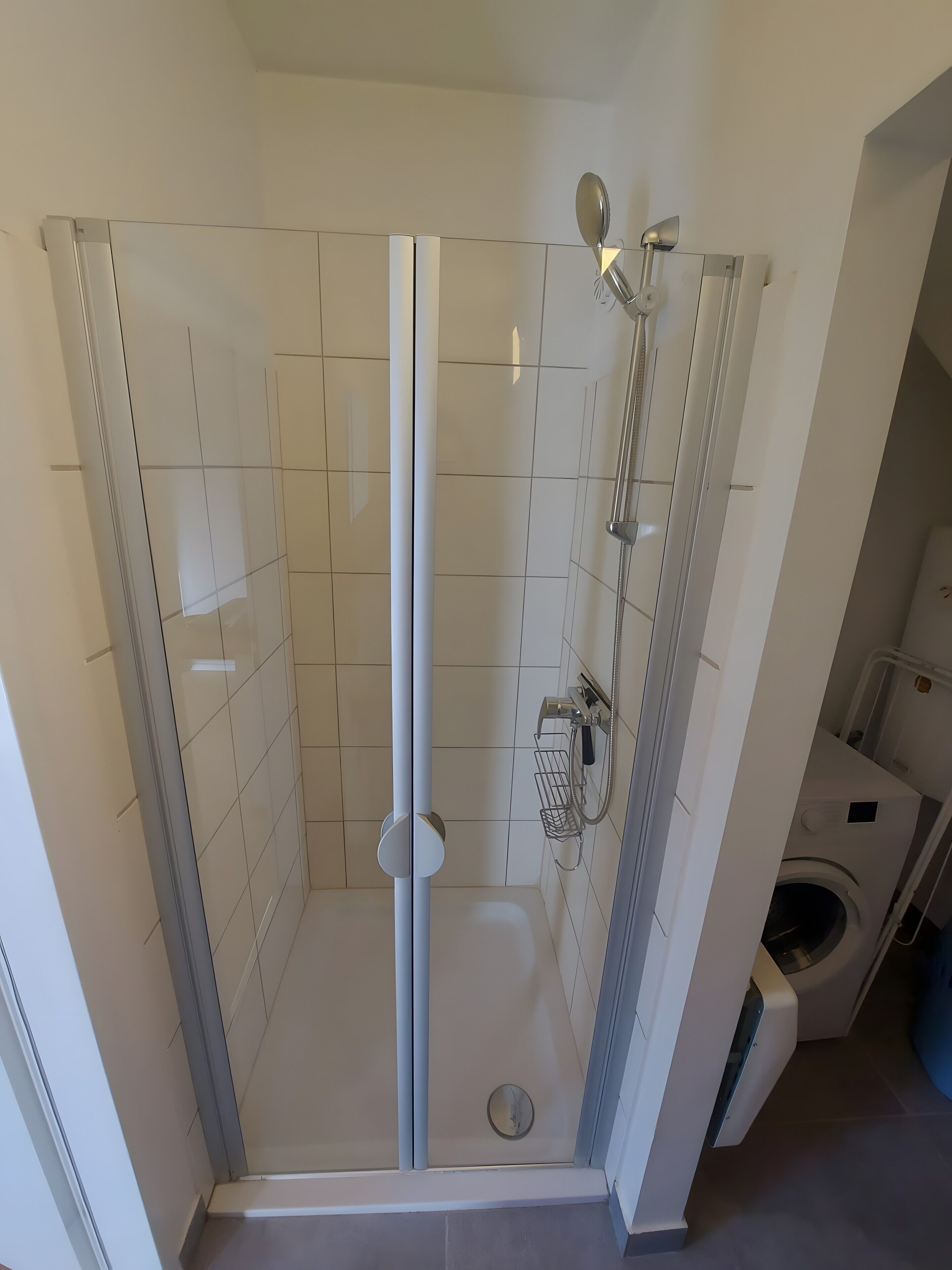 Eine separate Duschkabine mit Handbrause, Wandarmatur und Toilette im angrenzenden Raum.