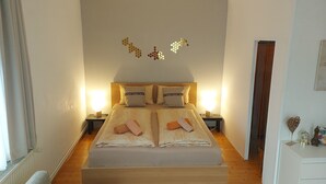 A double bed with two nightstands, a wooden headboard, and a wall decoration. - Apartment 'Golden Base' with Mountain View, Wi-Fi and Air Conditioning (Villach)
