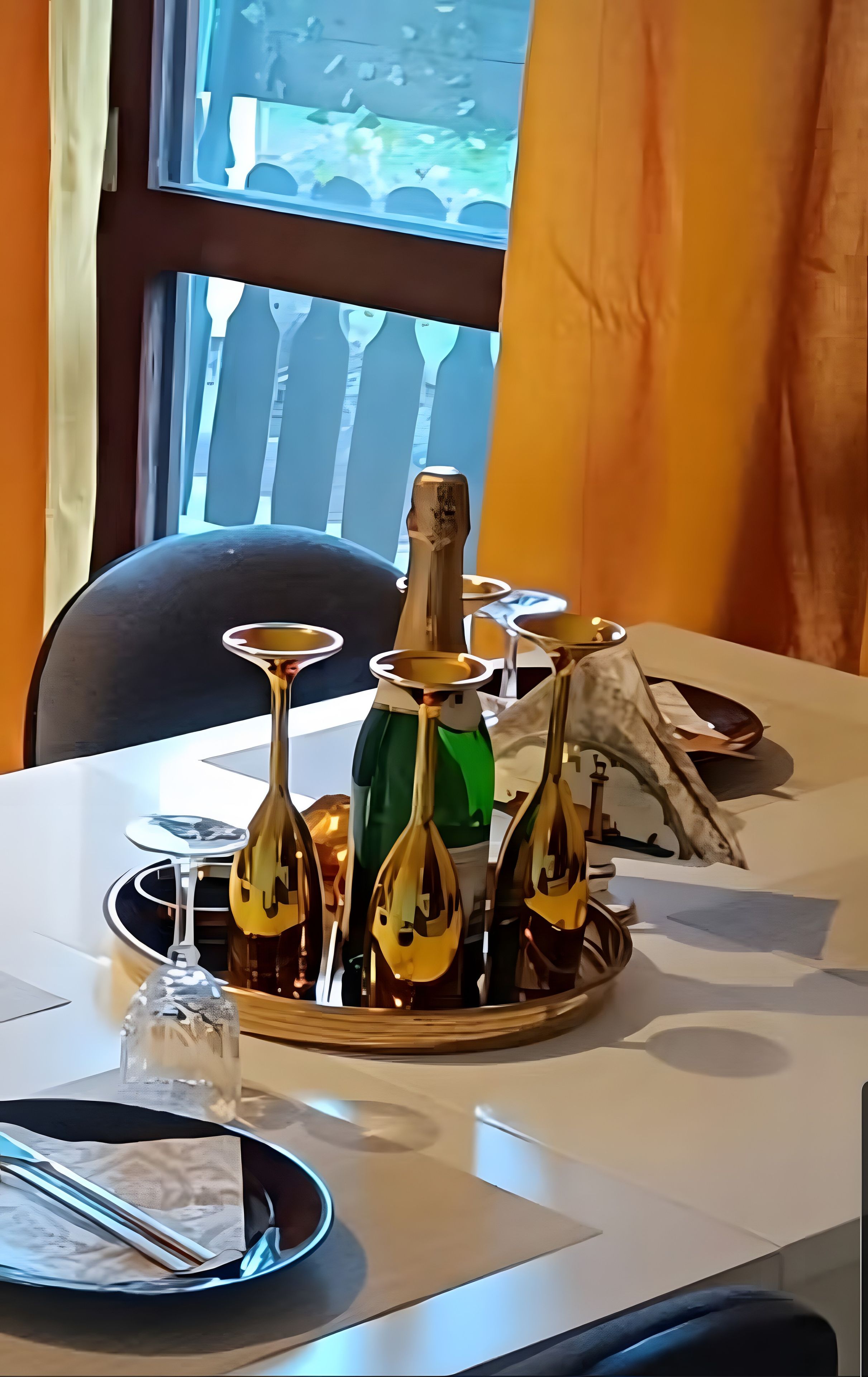 A table with a bottle of wine, wine glasses, and a decorative item.