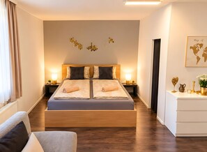 A modern hotel room with a large bed, bedside lamps, a small table with a plant, and a world map on the wall. - Apartment 'Golden Base' with Mountain View, Wi-Fi and Air Conditioning (Villach)