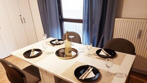 A dining table set with plates, cutlery, and glasses, with a bottle and a small bowl on the center. - Apartment 'Golden Base' with Mountain View, Wi-Fi and Air Conditioning (Villach)