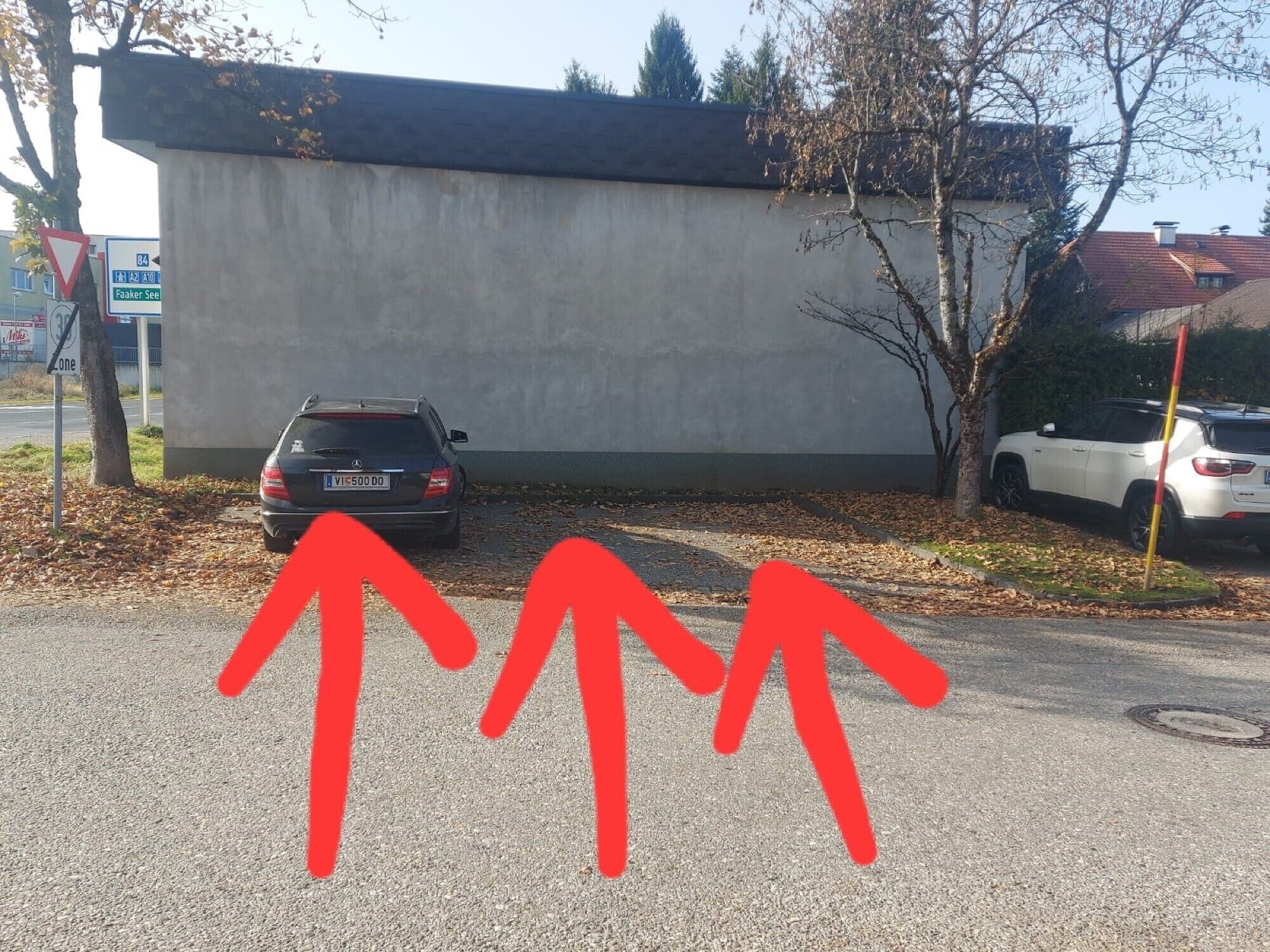 Un estacionamiento con dos autos estacionados frente a un edificio de fachada de concreto.