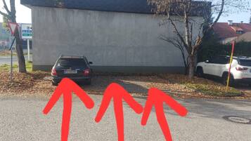 Ein Parkplatz mit zwei geparkten Autos vor einem Gebäude mit einer Betonfassade.