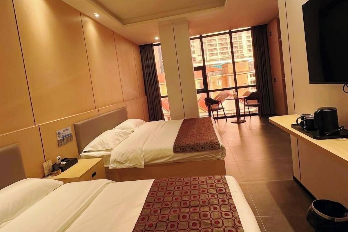 Habitación de hotel con dos camas, un escritorio, un televisor y vistas al exterior.