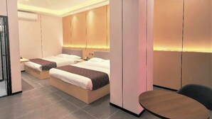 Une chambre d’hôtel moderne avec deux lits, une petite table et un coin salon.