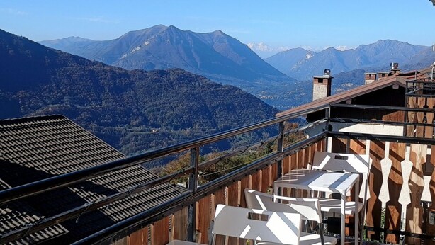 Eine Terrasse mit Bergblick, Holzwerteln und weißen Stühlen.
