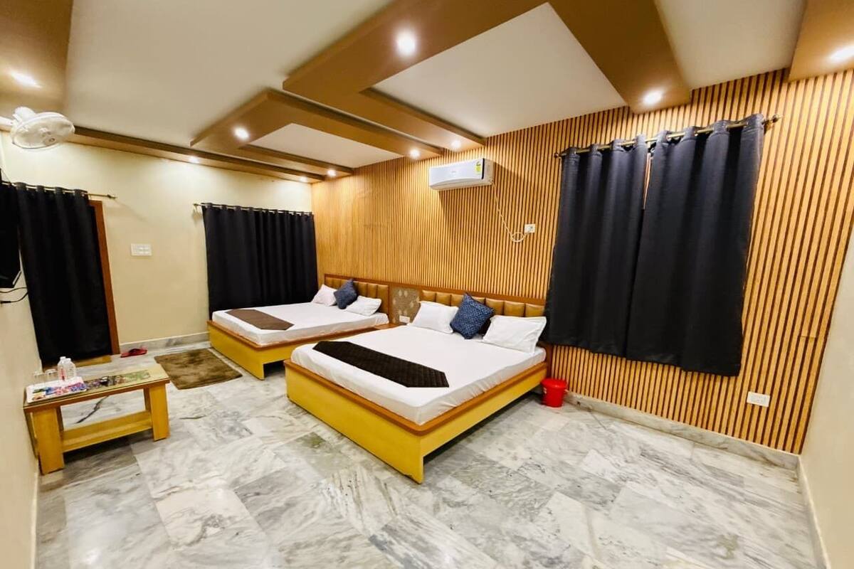 Ein Hotelzimmer mit zwei Betten, einem Holzkopfende, einem Marmorboden und einer Klimaanlage.