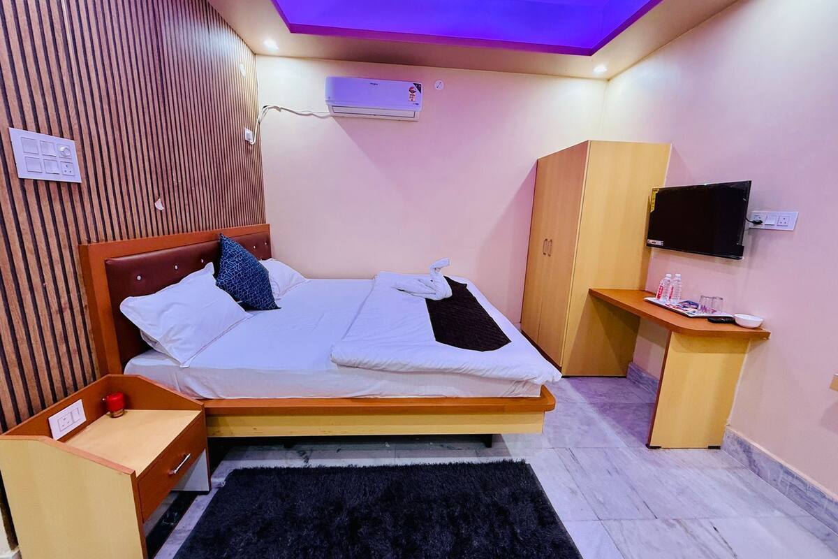 Ein Schlafzimmer mit einem Bett, einem Kleiderschrank, einem Fernseher und einem kleinen Tisch mit einer Wasserflasche.